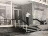 Black and white photo of a young man, Frank Thompson, on steps outside a building with BOOKSHOP on the wall behind him