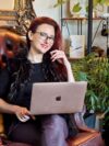 An author photograph of Rochelle Siemienowicz, holding a laptop on an armchair