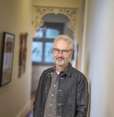 Josh Bornstein standing in a hallway with a black jacket and glasses, looking at the camera.