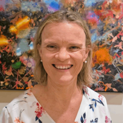 An author portrait of Kirsty Windeyer, who stands in front of an abstract artwork