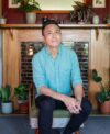 Photo of poet Chris Tse in front of a fireplace.