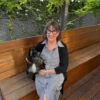Photo of Rosalie Ham on a garden bench with her dog.