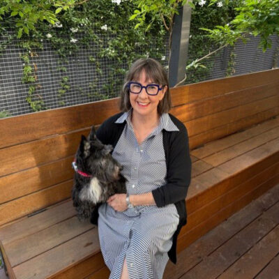 Photo of Rosalie Ham on a garden bench with her dog.