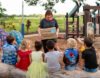 Woman showing parcel of books to children in remote community.