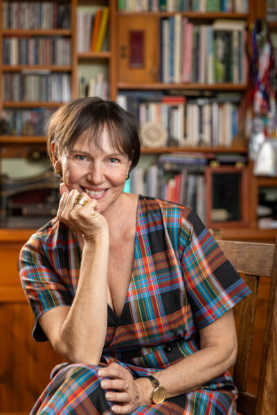 Photograph of Pip Williams sitting in front of a bookcase