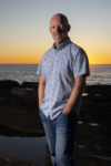 Photograph of Malcolm Knox standing in front of the ocean