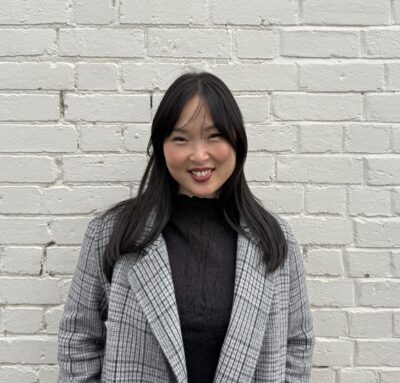 Photograph of Natika Palka standing in front of a white brick wall