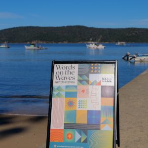 A Words on the Waves sandwich board sign in front of the ocean