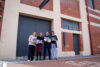 Four people standing in front of a building, holding books