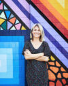 Woman standing in front of a colourful painted wall